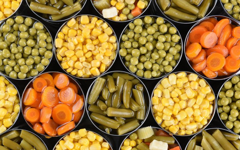 Group of open canned vegetables shot from a high angle. Assorted veggies carrots, corn, green beans, peas and mixed vegetables.